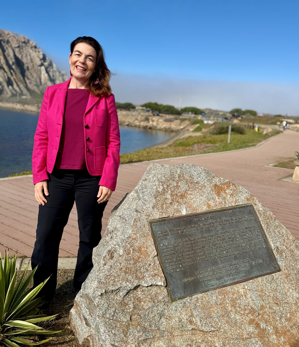 Asm. Addis standing next to monument of metal plaque on stone