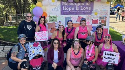 Asm. Addis with others wearing pink, with poster board in background, at the Lumina Alliance Celebrate Community Festival and March for Survivors