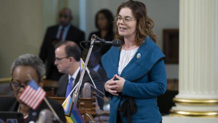 Asm. Addis standing, speaking into microphone on the Assembly Floor