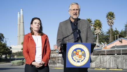 County Supervisor Glenn Church at podium, speaking as Asm. Addis stands in support