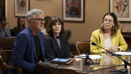 Witness providing testimony and fellow witness and Asm. Addis listen on