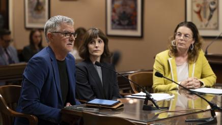 Witness providing testimony and fellow witness and Asm. Addis listen on