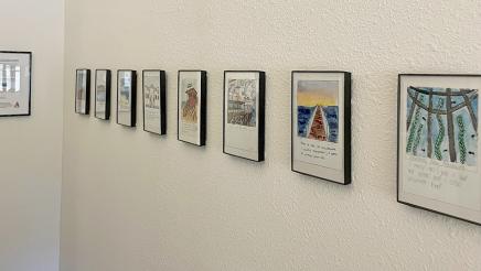 Multiple framed paintings with captions hanging on wall