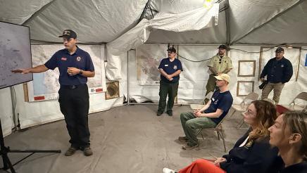 Asm. Addis seated, listening to briefing from first responder
